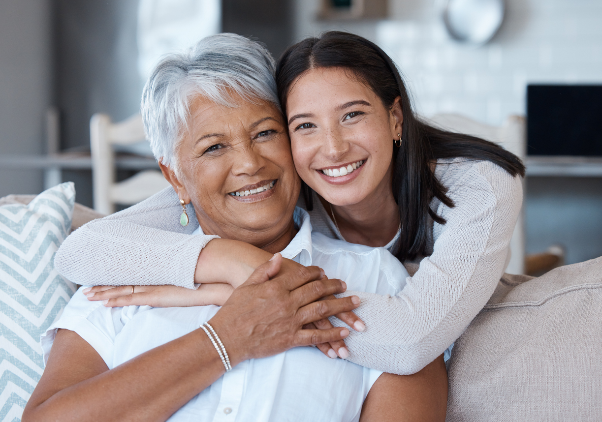 Senior resident at Traditions at Solana sitting on the couch with her daughter in her senior living apartment